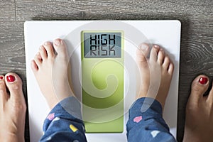 Childhood obesity high risk for health problems with childÃ¢â¬â¢s feet on weight scale under the supervision of his mother photo